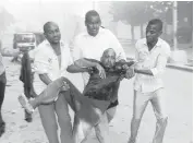  ?? FARAH ABDI WARSAMEH/ASSOCIATED PRESS ?? Somali men help a wounded civilian who was injured Saturday in a suicide car bomb attack on a hotel in Mogadishu, Somalia.