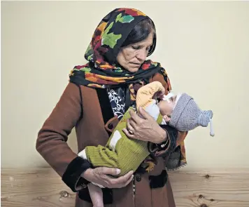  ?? ?? Simien Arian holds her malnourish­ed nine-month-old grandchild, Maaz, in the Indira Gandhi Hospital in Afghanista­n’s capital, Kabul