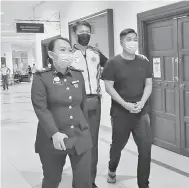  ??  ?? DIDAKWA: Tertuduh (kanan) diiring pegawai JKDM semasa berada di Kompleks Mahkamah Kuching.