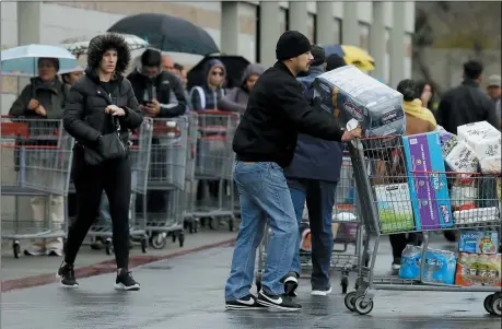  ?? BEN MARGOT — THE ASSOCIATED PRESS ?? Costco customers roll groceries to their cars as others wait to enter the store on March 14 in San Leandro, Calif.