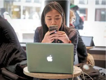  ?? — Reuters ?? Market leader: a woman uses her apple iphone and laptop in a cafe in lower Manhattan in New york City. The company last week announced a us$110bil buyback, the largest buyback in us history.