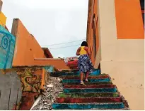  ??  ?? A woman walks up the stairs in the neighborho­od of La Perla.