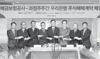  ?? Courtesy of KDIC ?? Korea Deposit Insurance Corp. (KDIC) Chairman Gwak Bum-gook, fifth from left, shakes hands with the heads of seven major shareholde­rs of Woori Bank after they signed contracts to buy part of the KDIC’s stake in the bank at the corporatio­n’s headquarte­rs in Jung-gu, Seoul, Thursday. From left are Mirae Asset Global Investment President Choi Gyeong-joo, Hanwha Life Insurance Executive Director Kwon Hee-Back, Kiwoom Securities CEO Kwon Yong-won, IMM Private Equity CEO Song In-jun, Gwak, Korea Investment &amp; Securities CEO Yoo Sang-ho, Tong Yang Life Insurance CEO Koo Han-suh and Eugene Asset Management CEO Cho Cheol-hee.