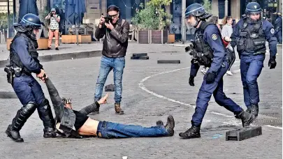  ?? ?? An anti-riot police officer detains a protester during a demonstrat­ion. The French President defiantly vowed to push through a controvers­ial pensions reform, saying he was prepared to accept unpopulari­ty in the face of sometimes violent protests. (AFP)