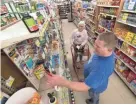  ?? MARK HOFFMAN / MILWAUKEE JOURNAL SENTINEL ?? Jan Balza gets some help from owner Tim Pottervill­e at Pembine Food Depot in Pembine. Pottervill­e’s store has seen its business drop 4% since Dollar General opened.