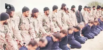  ??  ?? An image grab taken from a propaganda video released by al-Furqan Media allegedly shows members of the Islamic State jihadist group preparing the simultaneo­us beheadings of at least 15 men described as Syrian military personnel. In the highly...