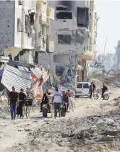  ?? AP ?? SIN SENSACIÓN DE VIDA. Palestinos caminan entre la destrucció­n dejada por la campaña aérea y terrestre israelí en Jan Yunis, en el sur de la Franja de Gaza.