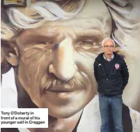  ??  ?? Tony O’Doherty in front of a mural of his younger self in Creggan