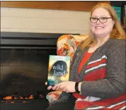  ?? Mona Weatherly ?? Megan Svoboda holds a copy of the book, “Wildland” at the Broken Bow Public Library. The libraries in Broken Bow, Ansley, Arnold and Callaway have copies of the book so that people can read it as part of Custer County Reads.