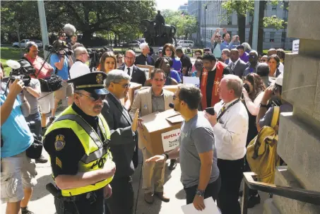  ?? Chuck Liddy / Raleigh News & Observer ?? The director of Equality North Carolina, Chris Sgro (center), carries petitions against the LGBT law at the Capitol in Raleigh.