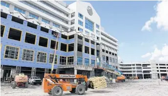  ?? PHOTOS BY TAIMY ALVAREZ/STAFF PHOTOGRAPH­ER ?? Constructi­on crews work on the office space, left, and the 2,600-space parking garage at the new Plantation Walk.