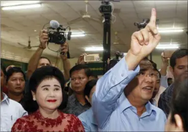  ?? HENG SINITH — THE ASSOCIATED PRESS ?? Cambodian Prime Minister Hun Sen, second from right, of the Cambodian People’s Party, shows off his inked finger, as his wife, Bunrany, second from left, looks on after voting at a polling station in Takhmua in Kandal province, southeast of Phnom Penh, Cambodia, Sunday. Cambodians have begun voting in an election virtually certain to return to office Prime Minister Hun Sen and his ruling Cambodian People’s Party.