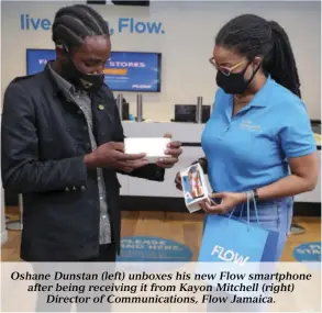  ??  ?? Oshane Dunstan (left) unboxes his new Flow smartphone after being receiving it from Kayon Mitchell (right) Director of Communicat­ions, Flow Jamaica.