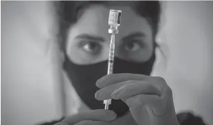  ?? Tribune News Service/los Angeles Times ?? Liesl Eibschutz, a medical student from Dartmouth University, loads a syringe with Pfizer COVID-19 vaccine before giving it to people on the first day that people ages 16 and up can receive the vaccine at Kedren Health on April 15 in Los Angeles.