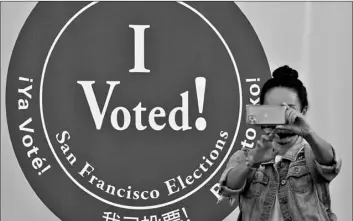  ?? AP Photo/Jeff Chiu ?? A woman takes a photo in front of an I Voted sign at a San Francisco Department of Elections voting center in San Francisco, on Monday ahead of Election Day.
