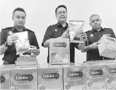  ??  ?? Khairul (centre) and two of his officers show the seized boxes of infant formula, believed to be fake. — Bernama photo