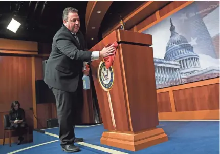  ?? SUSAN WALSH/AP ?? Mike Mastrian, director of the Senate Radio and Television Gallery, wipes down the podium Tuesday before a news conference on Capitol Hill led by Senate Majority Leader Mitch McConnell.