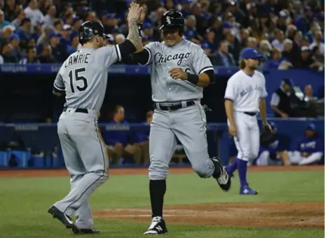  ?? TODD KOROL/TORONTO STAR ?? Chicago’s Brett Lawrie and Avisail Garcia celebrate scoring a pair of runs in the fifth inning of Tuesday’s 10-1 rout over the Blue Jays at the Rogers Centre.