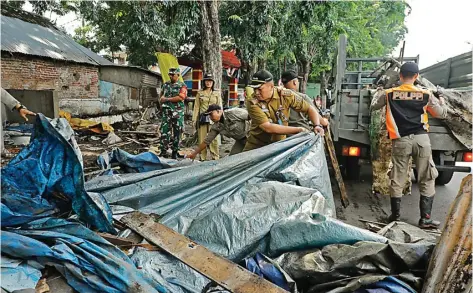  ?? DIPTA WAHYU/JAWA POS ?? BERADA DI ATAS SALURAN AIR: Camat Wonocolo Denny Christupel Tupamahu turun ke lapangan membersihk­an sisa lapak PKL di Jalan Raya Margorejo kemarin.