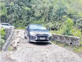  ?? PHOTOS BY BRYAN MILLER ?? A car drives on the wooden structure fixed by residents at the Woodsville Bridge in Woodsville, Hanover.