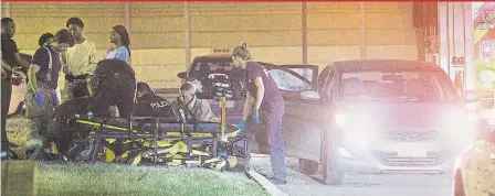  ?? JOHN HANLEY ?? Police and paramedics attend to the victim of a drive-by shooting near Lawrence Ave. and Allen Rd. early Sunday. The victim, a 31-year-old woman, later died in hospital.