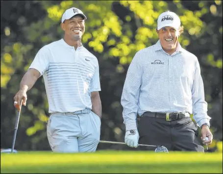  ?? Curtis Compton The Associated Press ?? Tiger Woods, left, and Phil Mickelson share a laugh while playing a practice round for the 2018 Masters at Augusta National Golf Club. The two will play a charity event Sunday for COVID-19 relief efforts.