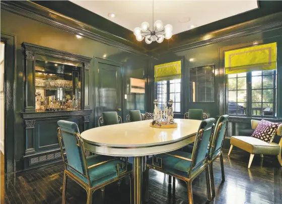  ?? Open Homes Photograph­y ?? The formal dining room at 124 21st Ave. in the Lake district offers a chandelier, a mirrored bar and a green lacquer finish.