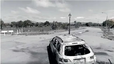  ??  ?? An eerie scene of a deserted street and abandoned car in the Tom Dale’s The Red Zone.