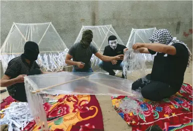  ?? (Ibraheem Abu Mustafa/Reuters) ?? PALESTINIA­NS IN GAZA prepare kites loaded with flammable material to be launched into Israel.