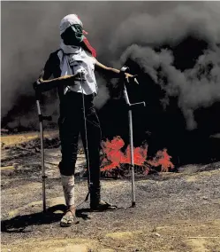  ?? SPENCER PLATT/GETTY IMAGES ?? A wounded Palestinia­n protester stands at the border fence with Israel on Monday during a mass demonstrat­ion in Gaza City.