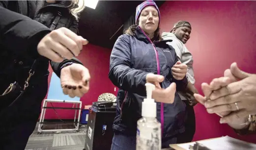  ?? JAMES FOSTER/SUN-TIMES ?? Sharon Trask and other voters use hand sanitizer as they vote March 17 at the Lincoln Lodge polling station in Chicago.