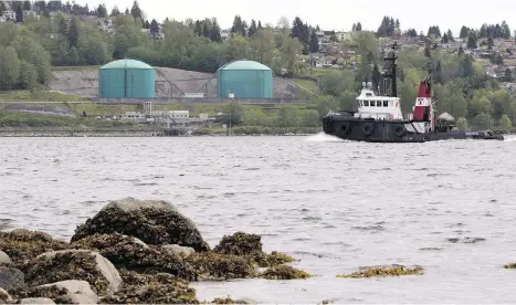  ?? JONATHAN HAYWARD/THE CANADIAN PRESS FILES ?? A tug boat chugs past the Kinder Morgan Marine Terminal. Many British Columbians are increasing­ly uncomforta­ble with a decade of pipeline wars that are harming the province’s attractive­ness as a place to do business, writes Claudia Cattaneo.