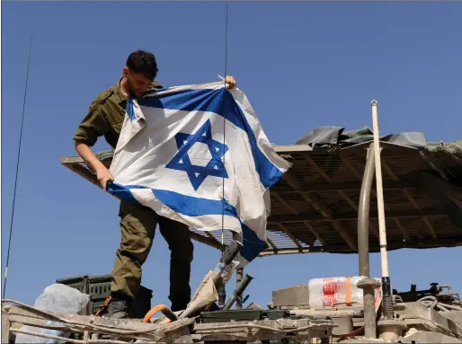  ?? Picture: Amir Levy/getty Images ?? An Israeli soldier hangs his country’s flag on an armoured personnel carrier near the border with the Gaza Strip