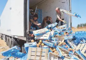  ?? AFP ?? Russian workers throw peaches off a truck in Moscow Friday.