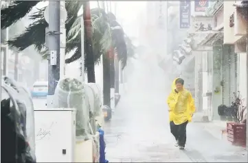  ??  ?? A passer-by walks in heavy rain and wind caused by Typhoon Trami in the prefectura­l capital Naha, on the southern island of Okinawa. — Reuters photo