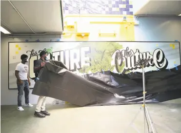  ?? Lea Suzuki / The Chronicle ?? At the Coliseum BART Station on Friday, Jordan Hill (left) and Hezekiah Pemberton unveil the mural that they helped plan during their internship.