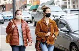  ??  ?? Shelly Thorene / Union Democrat Elizabeth Lee (left), and her daughter, Jessica, both of Escalon, wear masks as they shop Friday in downtown Sonora. Revive coffee shop on South Washington Street lightens the mood with trivia on their spacers for customers waiting in line (left)