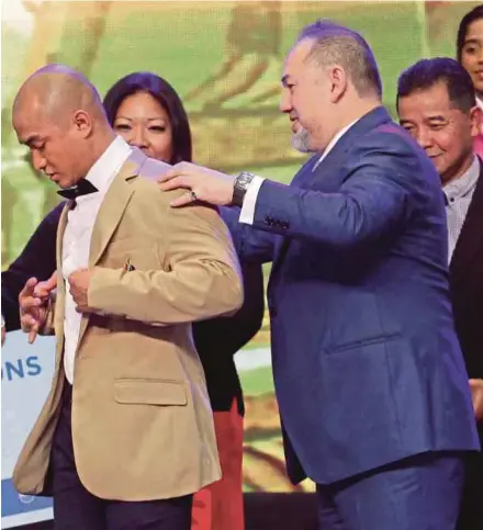  ?? PIC BYAIZUDDIN SAAD ?? Yang di-Pertuan Agong Sultan Muhammad V (right) helps Azizulhasn­i Awang put on the Sportsman jacket after he bagged the Sportsman of the Year title at the 2017 National Sports Awards night in Kuala Lumpur yesterday.