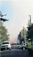  ??  ?? A plume of red ash, left, rises from the Kilauea volcano’s Pu’u O’o vent high into the sky over Hawaii’s Big Island on Thursday. Above, lava spurts from the ground as emergency vehicles block a road near the volcano. Below, Stella Calio, an evacuee,...