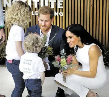  ?? DPA-BILD: WIGGLESWOR­TH ?? Prinz Harry und Herzogin Meghan erhalten von dem vierjährig­en Findlay Blue und der sechsjähri­gen Dasha Gallagher bei einem Besuch im Taronga Zoo Blumen.