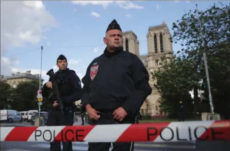  ?? CHRISTOPHE ENA — THE ASSOCIATED PRESS ?? Police officers seal off the access to Notre Dame cathedral, seen in the background, after a man attacked officers with a hammer outside the famous landmark, in Paris, France, Tuesday. The Paris prosecutor’s office said the investigat­ion was opened...
