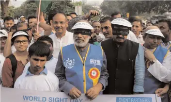  ?? — BIPLAB BANERJEE ?? Blind-folded minister of state Alphons Kannanthan­am and Delhi BJP chief Manoj Tewari lead the Blind Walk-2017 in New Delhi on Thursday to raise awareness about eye donation.