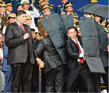  ?? Foto: Xin Hua, dpa ?? Sicherheit­sbeamte schützen den venezolani­schen Präsidente­n Nicolás Maduro, nachdem seine Rede unterbroch­en wurde. Wäh rend einer Militärpar­ade in Venezuela hat es wohl einen versuchten Anschlag gegeben.