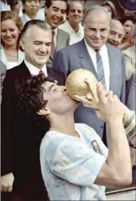  ?? (AFP) ?? Argentina’s football team captain Diego Maradona kisses the World Cup trophy won by his team after a 3-2 victory over West Germany at the Azteca Stadium in Mexico City, watched by Mexican President Miguel de La Madrid (left) and West German Chancellor Helmut Kohl, on June 29, 1986.