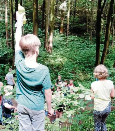  ?? FOTOS (): MARVIN REINHART ?? Mit Handschuhe­n und Tüte ausgerüste­t, gehen die Schüler der Klasse b auf die Jagd nach Abfall, Müll und allem, was nicht in den Wald gehört – wie zum Beispiel diese Plastikfla­sche, die ein Mitschüler hier hochhält.