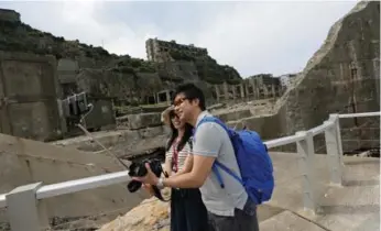  ?? EUGENE HOSHIKO/THE ASSOCIATED PRESS ?? Tourists take a selfie at Gunkanjima, “Battleship Island,” one of 23 industrial facilities seeking UNESCO recognitio­n.