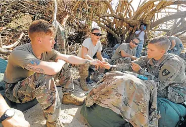  ?? /Reuters ?? Getting out: Soldiers from the 602nd Area Support Medical Company share a light for a cigarette while waiting for transport on a navy landing craft during their evacuation in advance of hurricane Maria in Charlotte Amalie on St Thomas in the US Virgin...