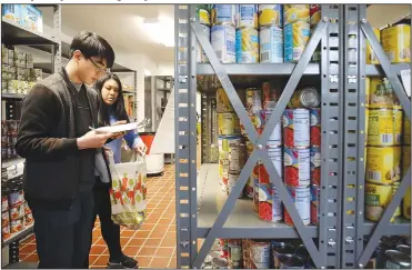  ?? NWA Democrat-Gazette/DAVID GOTTSCHALK ?? Johnny Down (left), a sophomore at the University of Arkansas, volunteers Thursday with his sister Jenny, a junior, to fill an order for a client at the Jane B. Gearhart Full Circle Food Pantry on the Fayettevil­le campus. The pantry celebrated an opening Thursday following a remodel increasing its storage capacity by 40 percent and the eighth anniversar­y of the pantry. The student-run program offers assistance to students, faculty, staff and their families who are facing food insecurity or in need of supplement­al food.