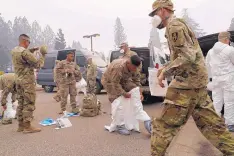  ?? JOHN LOCHER/ASSOCIATED PRESS ?? Members of the Army National Guard put on protective suits in preparatio­n to search for human remains of victims of the Camp Fire in Paradise, Calif., on Wednesday.