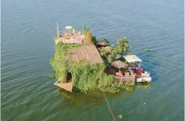  ?? PATRICK ONEN/AP ?? A floating restaurant and bar is seen from the air Feb. 18 in Lake Victoria near the Luzira area of Kampala, Uganda. Flowering plants rise from the water into the hull.